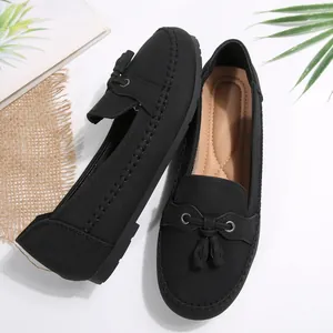 Detailed view of women's black loafers with tassel decoration and hand-stitched details