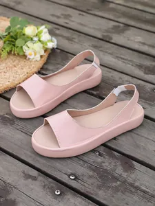 Close-up detail of pink platform peep-toe slingback sandals on a wooden deck with a straw hat