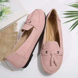 Close-up view of elegant pink suede loafers featuring stylish tassels and stitching