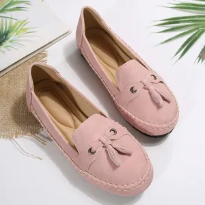 Top view of pink suede loafers with decorative tassels and stitching details