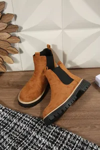 Eleganti stivaletti Chelsea in pelle scamosciata con spessa suola nera su pavimento in legno
