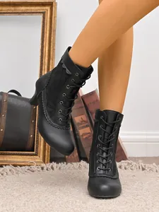 Gros plan sur des bottines à lacets noires avec inserts latéraux en dentelle et bords festonnés