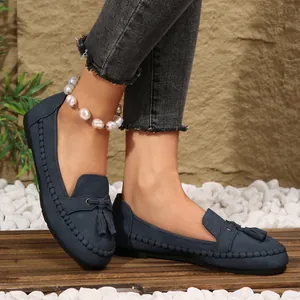 Detailed macro shot of navy blue suede women's loafers featuring tassels and whipstitched edges