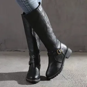 Close-up view of stylish black knee-high riding boots featuring metal buckle straps.