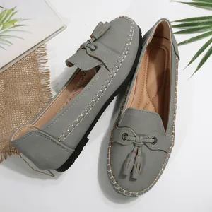 Close-up of grey women's tassel loafers with white stitching and padded tan insole.