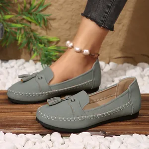 Elegant grey slip-on loafers for women with tassel detail shown in an outdoor setting