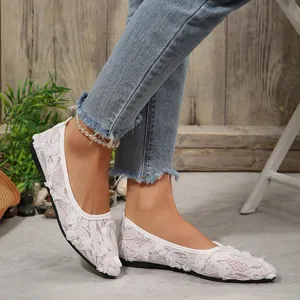 Close-up detail of white lace pointed-toe flat shoes featuring elegant floral embroidery
