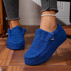 Detailed shot of cobalt blue fleece-lined slip-on loafers being worn by a model on wooden floor