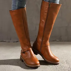 Close-up of brown faux leather tall riding boots with side zipper and ankle buckle strap
