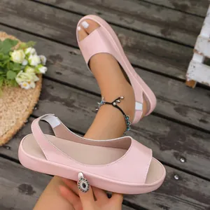 Detailweergave van roze peep-toe platte sandalen met elastische band op een houten