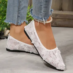 Detailed view of white lace pointed-toe flat shoes worn with denim jeans for summer.