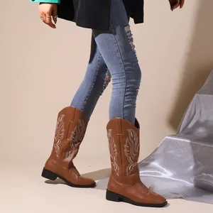 Close-up detail of brown western cowboy boots featuring intricate white embroidery