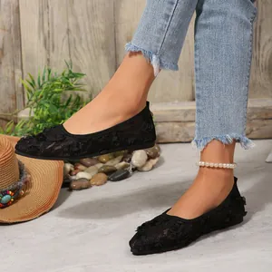 Close-up of black lace pointed toe flat shoes with floral embroidery details.