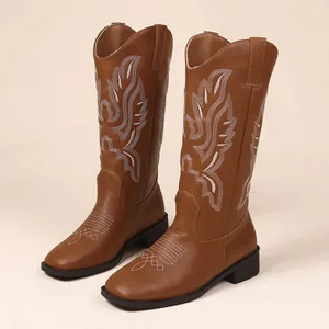 Close-up view of vintage brown western cowboy boots with intricate white embroidery