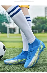 Blue high-top soccer cleats with sock collar and silver lightning graphics on turf