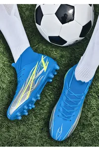 Detail view of blue high-top soccer shoes with flame pattern on artificial grass.