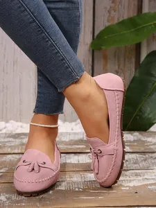 Close-up of pink suede loafers for women with stylish tassel and hand-stitched details.