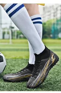 Close-up of high-top fly-knit football boots with dynamic gold patterns on turf