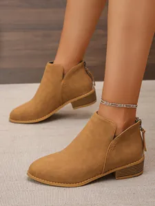 Close-up of stylish brown suede ankle boots featuring tassel zipper and side cutouts