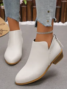 Detailed view of white leather ankle boots with pointed toe and back zipper closure