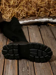 Detail view of the rugged platform sole and elastic fabric of the black over-the-knee boot.