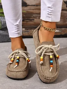 Nahaufnahme von Vintage-Wildleder-Loafers mit Seilschnürsenkeln und bunten Perlen-Details
