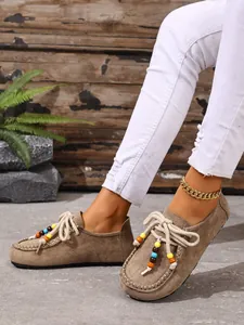 Detailansicht brauner Wildleder-Loafer mit bunten Holzperlen und dicken weißen Schnürsenkeln