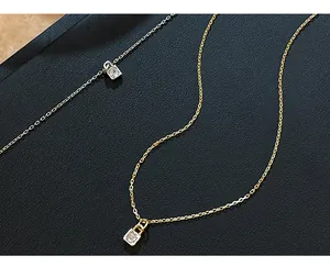 Detailed view of two delicate padlock pendants with single crystals on fine chains.