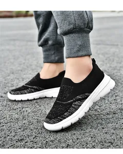 Dettaglio laterale di scarpe da camminata in mesh fly-knit traspirante su ghiaia
