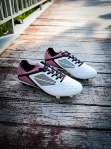 Professional unisex soccer cleats with FG/HG studs on a rustic wooden boardwalk path.