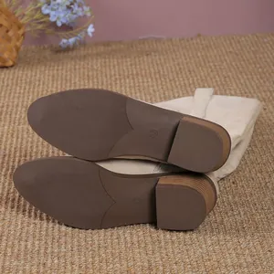 Détail des semelles antidérapantes brunes et talons épais de bottes western beige