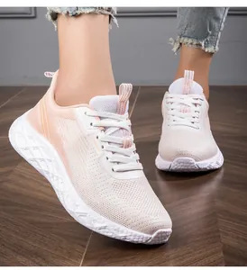 Detailed close-up of breathable mesh texture on peach and white women's running sneakers