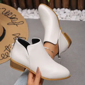 Detalle de botines blancos de punta fina con cremallera trasera y tacón de bloque