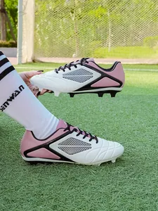 Professional pink and white leather soccer cleats for youth and adults on green turf