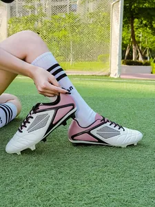 Detailed shot of professional pink and white soccer cleats on a green football grass pitch