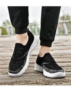 Vista dettagliata di sneaker in mesh flyknit bianche e nere su un ponte in legno