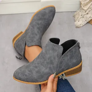 Detalle de botines de cuero gris texturizado con punta afilada y cremallera en la parte trasera