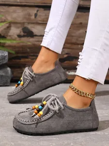 Detail der grauen Wildleder-Loafer mit bunten Perlen und goldenem Fußkettchen