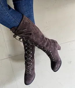 Close-up of brown suede lace-up mid-calf boots with chunky heel and round toe
