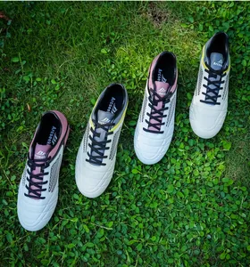 Detailed view of white soccer cleats with pink and yellow accents on green grass