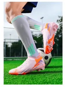 Gedetailleerde weergave van roze fly-knit voetbalschoenen op een groen kunstgrasveld.