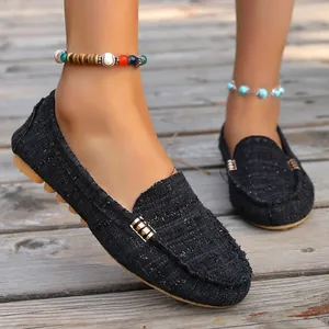 Close-up of black woven flat loafers with round toe and metal detail on wooden deck