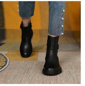 Front view of black flat leather ankle boots worn with pearl-detailed denim jeans