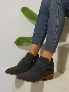 Detailed side view of grey pointed-toe Chelsea boots with cross straps and mid block heel
