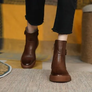 Stylish brown flat leather ankle boots with a retro design worn on a cozy carpet