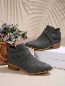 Detailed side view of grey pointed-toe Chelsea boots featuring cross-straps and buckle
