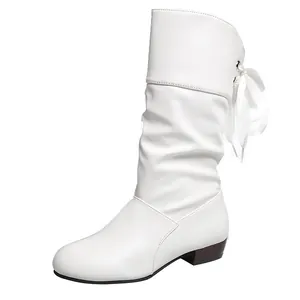 Detalle lateral de una bota blanca con pliegues y un lazo de cinta de seda atrás.