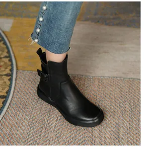Close-up view of black leather flat ankle boot featuring a stylish side buckle detail and round toe