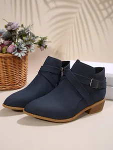 Side profile detail of navy blue pointed-toe Chelsea boots with cross buckle straps.