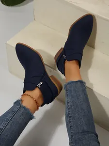 Detailed view of navy blue pointed-toe Chelsea boots with side zipper and cross straps.